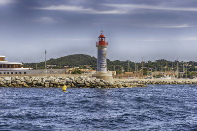 Lighthouse by sea against sky