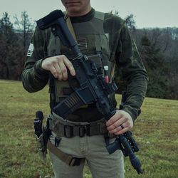 Full length of senior man holding camera on field