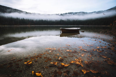 Boat moored in calm lake against trees