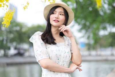 Portrait of young woman looking away while standing outdoors