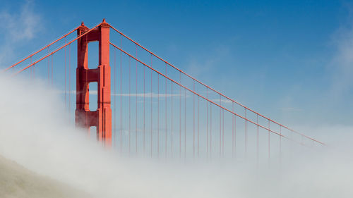 Low angle view of suspension bridge against sky