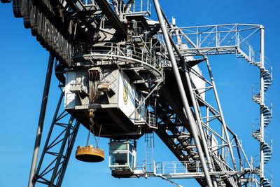 Low angle view of crane against clear blue sky