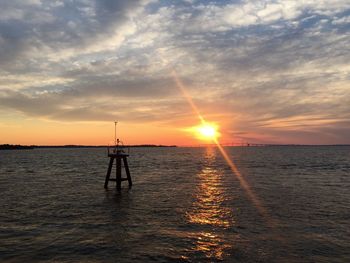 Silhouette man standing in sea against sky during sunset