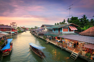 Canal amidst buildings against sky during sunset