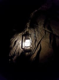 Low angle view of illuminated light bulb hanging at night