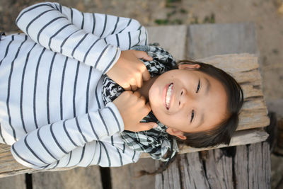 Overhead view of smiling girl lying on wooden log