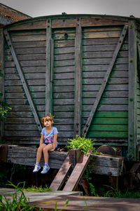 Side view of woman sitting on wooden door