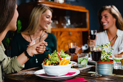 Happy young woman sitting at restaurant table