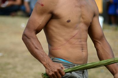 Midsection of shirtless man standing outdoors