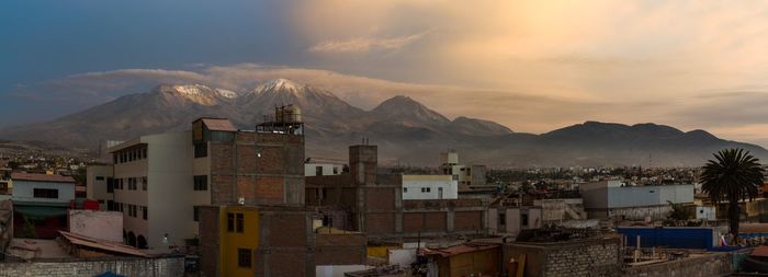 Townscape by mountains against sky during sunset