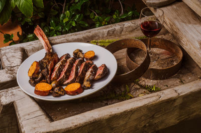 High angle view of steak with wineglass and salad in plate on table