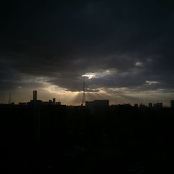 Silhouette of city against cloudy sky