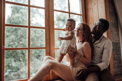 Young couple sitting on window at home