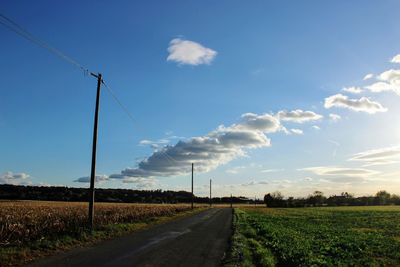 Road amidst field against sky