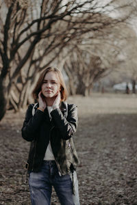 Portrait of young woman standing against bare trees