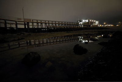 Illuminated bridge over sea against clear sky at night