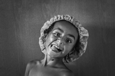 Close-up portrait of shirtless girl making face against wall