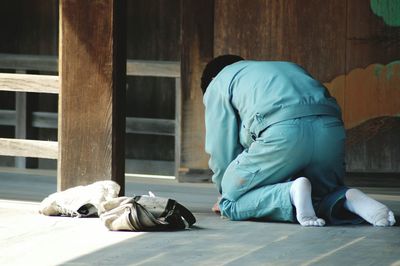 Rear view of man kneeling down on floor