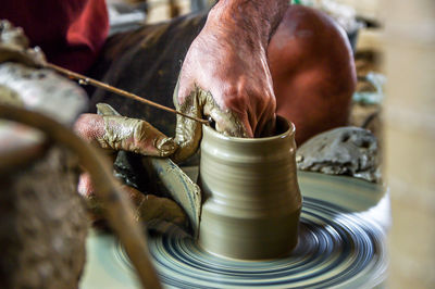 Cropped hands shaping earthenware on pottery wheel