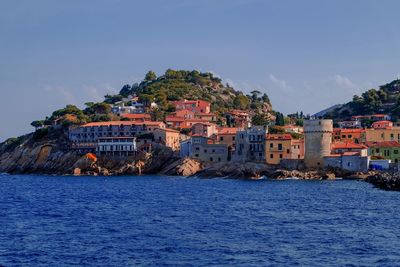 Buildings by sea against clear sky