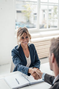 Smiling businesswoman shaking hands with man at office