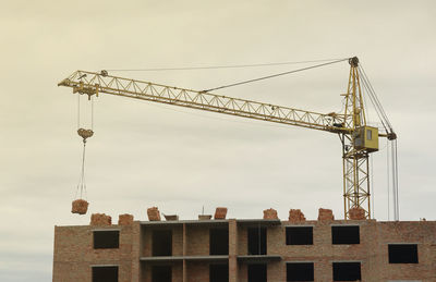 Low angle view of crane against sky