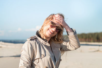 Portrait of smiling young woman standing against sky