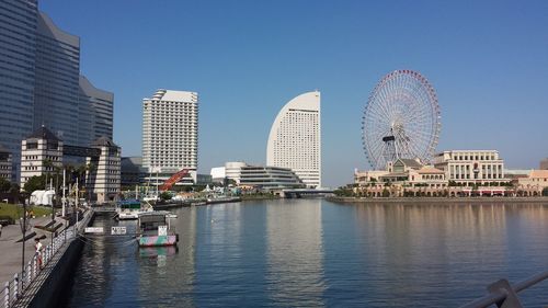 Ferris wheel by buildings in city against clear sky