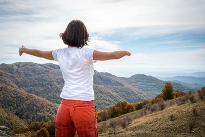 Rear view of woman standing on mountain against sky