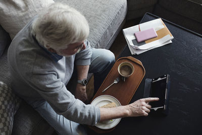 High angle view of senior man using digital tablet while having breakfast at home