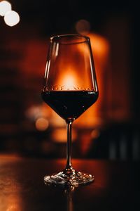 A glass of red wine on a wooden table in the evening bokeh light