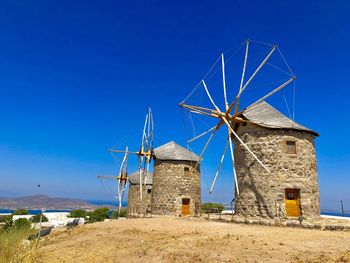 Traditional windmill on landscape against clear blue sky