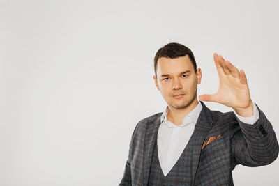 Portrait of young man standing against white background