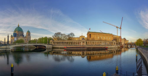 Bridge over river by buildings against sky in city