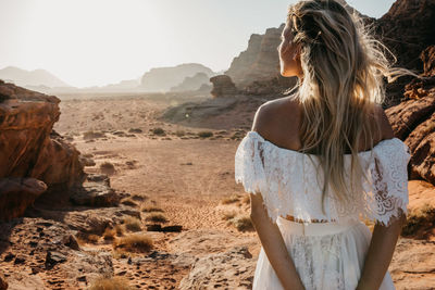 Rear view of woman standing on desert against sky