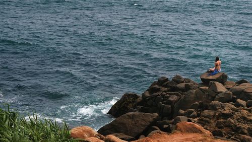 Man sitting on rock by sea