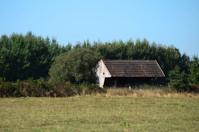 House on field against clear sky