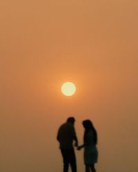 Low angle view of silhouette man standing against orange sky