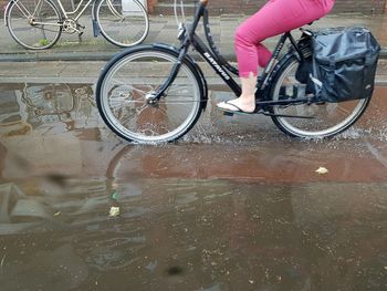 Low section of person with bicycle on puddle