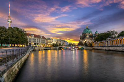 River amidst buildings against sky during sunset