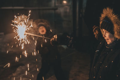 Boy holds a sparkler in his hands while celebrating a new year on the street at night. 