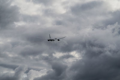 Low angle view of airplane flying in cloudy sky