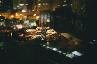 Reflection of building on glass while man working on laptop