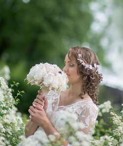 Young bride smelling white bouquet