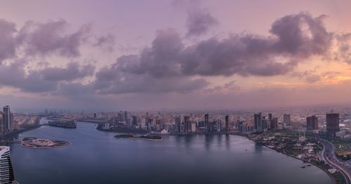 Panoramic view of river and buildings against sky at sunset