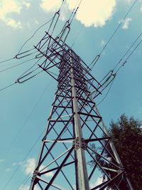 Low angle view of electricity pylon against cloudy sky