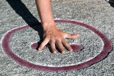 Cropped hand of man touching symbol on floor