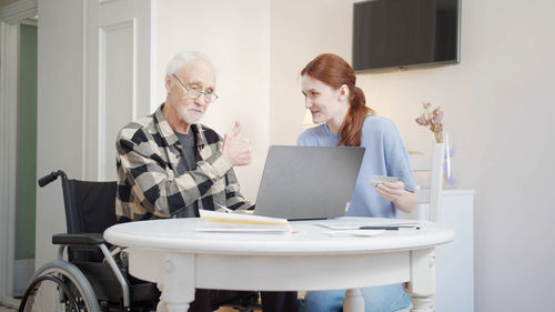 Side view of young woman using digital tablet while sitting at home