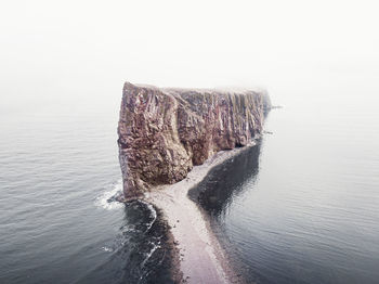 Rock formation in sea against clear sky