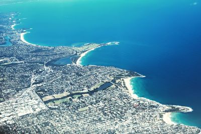 Aerial view of sea by cityscape against sky